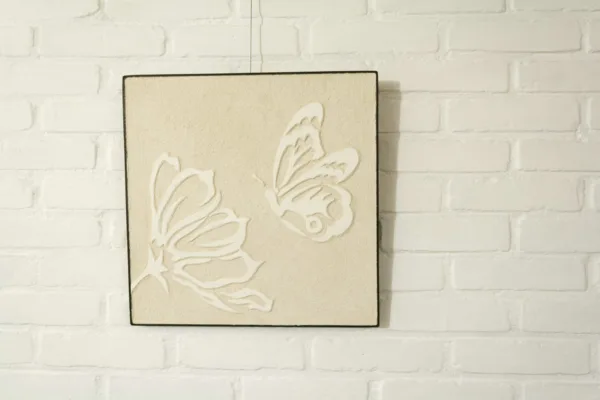 A hand-crafted sgraffito panel decorates a brick wall finished with Artisan Stucco Ebro White Lime Wash. Natural lime surfaces offer a beautiful backdrop for art and personal accents, blending timeless tradition with individual style.