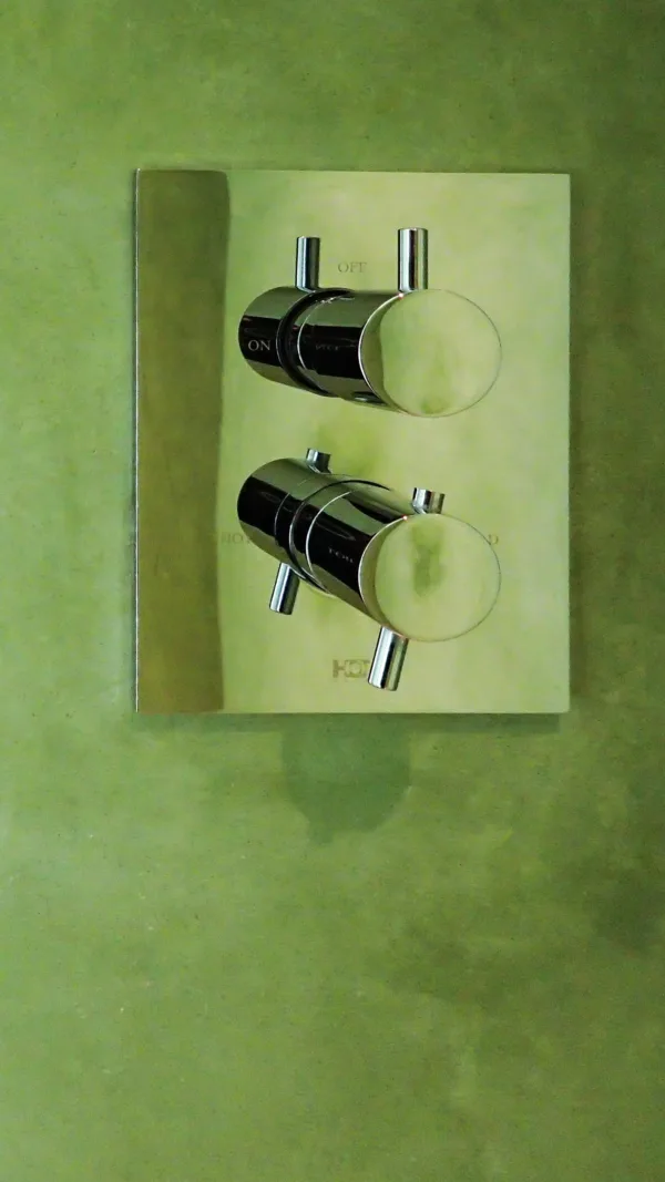 A close-up of the shower controls against the vibrant backdrop of Artisan Stucco Chrome Green waterproof plaster. Captured in a newly built home in Amsterdam.